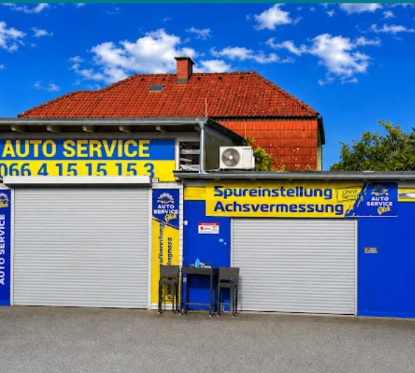 Werkstatt von Autoservice Oleh an der Kärntner Straße 105: blau-gelbe Fassade mit zwei Rolltoren und dem Banner Spureinstellung und Achsvermessung